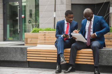 Açık havada iki Afro-Amerikan işadamının dostça buluşması. Ortaklar bankta oturup ortak bir projeyi tartışırlar.