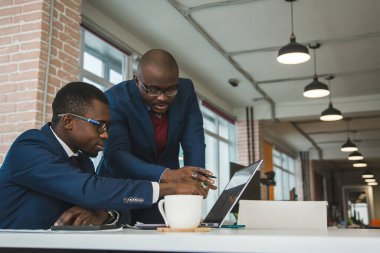 Afrika kökenli Amerikalı bir iş adamının iki esmer ortağı ofiste dizüstü bilgisayarla iş yapıyorlar. Uygun fiyatlı özel kurslar ve uzaktan öğrenme. İnternette yeni fırsatlar