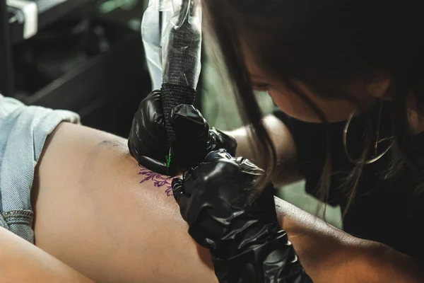プロの女性タトゥーアーティストは、スタジオでタトゥーを作ります,クローズアップ.暗い写真 — ストック写真