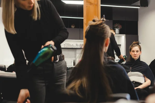 Maestra mujer peluquería seca el pelo de las niñas con un secador de pelo después de lavarse en un salón de belleza. — Foto de Stock