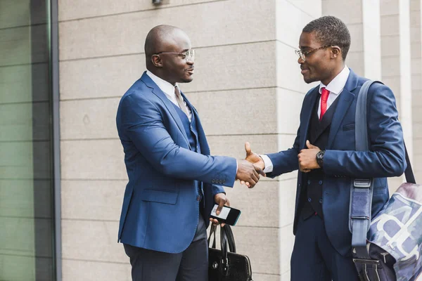 Retrato de dos hombres de negocios afroamericanos negros con trajes que se dan la mano al aire libre. La alegría de conocer buenos amigos — Foto de Stock