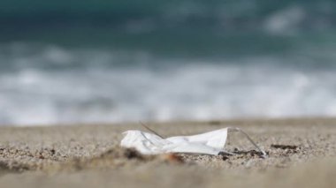 Koronavirüs salgınının sonuçları. Korunma yoluyla doğanın kirliliği. Kullanılmış maske artık plajda çöp.