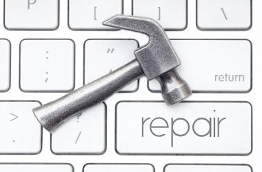 Küçük çelik çekiç klavyenin üzerinde duruyor, onarım olarak etiketlenmiş bir anahtar var. Donanım hizmeti kavramı.