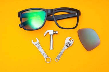 Kırık güneş gözlüğü ve sarı arka planda el aletleri. Onarım servisi kavramı.