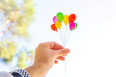 Elinde renkli minik plastik balonlar var.