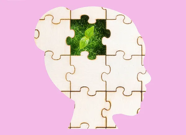 女人的头部轮廓形状的拼图与一个绿色的芽可见通过遗失的一块粉红色的背景 发展绿色思维的概念 — 图库照片