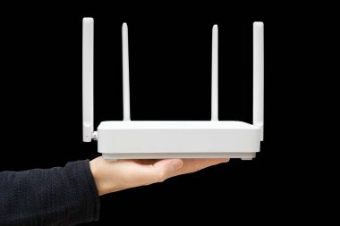 Erkek el, siyah arka planda modern çift şeritli yönlendirici tutuyor. Wi-Fi 6 'ya yükseltiliyor.