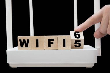 Parmak, Wi-Fi 5 'ten WiFi 6' ya geçişi gösteren tahta bir küpü döndürüyor. En son kablosuz ağ standardını desteklemek için altyapı değiştiriliyor.