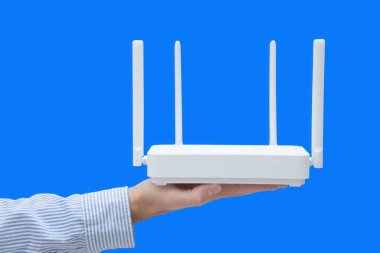 Mavi arka planda kablosuz yönlendirici tutan bir iş adamının yakın çekimi. Ofiste kablosuz ağ var..