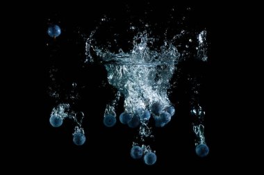 Taze yaban mersini suya düştü ve siyah arka plana sıçradı.