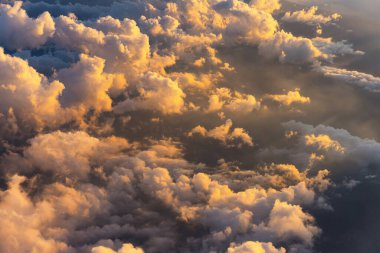 Scenic aerial view of the fluffy colorful clouds as seen from the aircraft window at sunrise.
