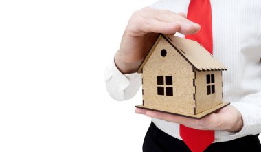 Beyaz arka planda bir el izole edilmiş ev modelini kapsayan satıcı. Gayrimenkul ve ticari emlak sigortası kavramı.