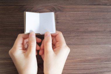 Tahta bir masa arkasında boş sayfaları olan minyatür bir kitabı tutan kadın eli görüntüsü. Eğitim ve öğrenme kavramı.