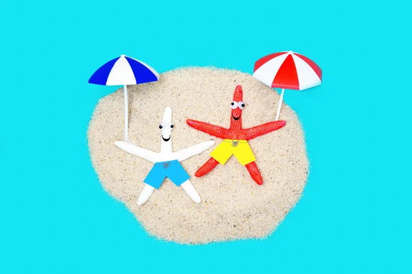 两个滑稽的海星角色 长着谷歌式的眼睛 在沙滩度假时享受阳光 — 图库照片