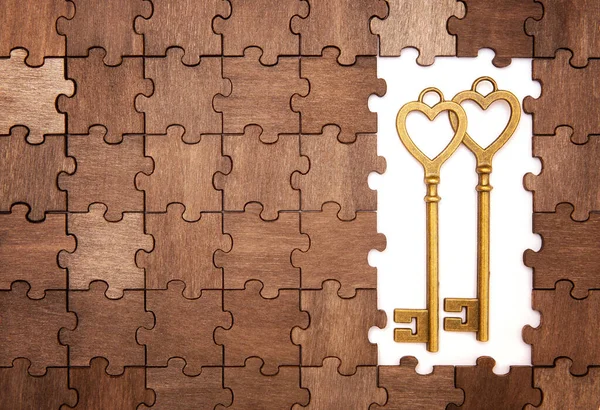 木制拼图背景图上两个复古风格青铜色调心形钥匙 — 图库照片