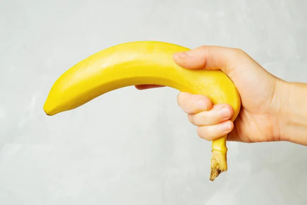 Vrouwelijke Hand Met Een Verse Rijpe Banaan Tegen Een Neutrale — Stockfoto