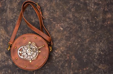 Arka planda saat mekanizması olan deri çantanın etrafını sarın..