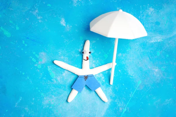 Happy white starfish character floating on a light blue background with a white parasol in hand. Positive sea vacation concept.