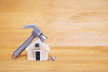 Küçük çelik çekiç ve çiviler tahta arka planda minyatür bir oyuncak evin yanında. Ev yenileme konsepti.