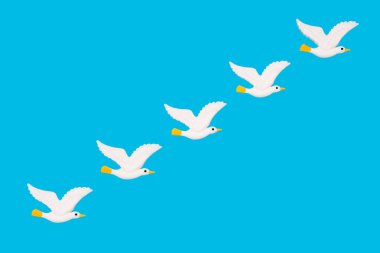 Açık mavi arka planda beş beyaz plastik kuştan oluşan yaratıcı yaz tatili arka planı. Gökteki martıların taklidi..