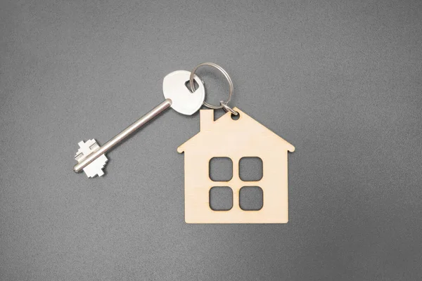 Düz ahşap ev şekilli anahtarlık. Gri bir arkaplanda izole edilmiş anahtarlık. Kopya alanı var..