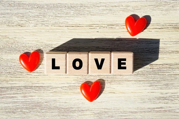 LOVE arrangement made from wooden letter blocks and red hearts on a wooden table.