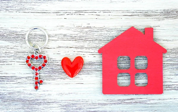 Takma elmaslarla süslenmiş iskelet anahtar, kırmızı ev şekilli anahtarlık ve tahta arka planda küçük bir kalp. Yaratıcı birlikte hareket etme kavramı.