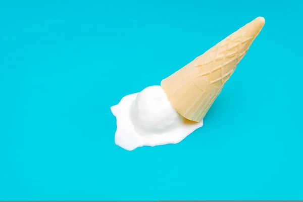 Dropped waffle cone ice cream isolated on a blue background with copy space. Pessimism and optimism concept.