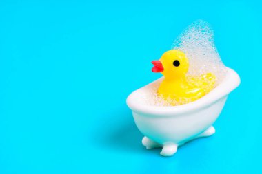 Sabun köpükleriyle kaplı küçük beyaz bir küvette sarı yavru ördek. Çocukların banyo zamanı konsepti..
