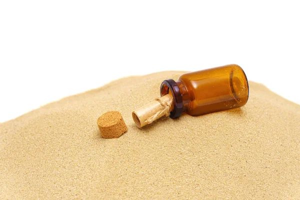 Tiny glass bottle with a message roll on a sand dune isolated on white. Castaway concept.