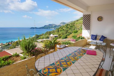 LETOJANNI, ITALY MAY 6, 2019: Working outdoors at a mediterranean style villa terrace with a gorgeous Ionian sea view