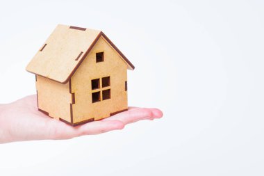 Small toy wooden house model in hand isolated on white background. Real estate investment concept.