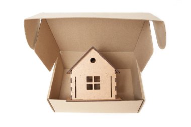 Wooden toy house inside a cardboard box isolated on white. Relocation concept.