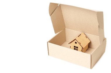 Cardboard box with a tiny wooden house inside. Buying a new home.