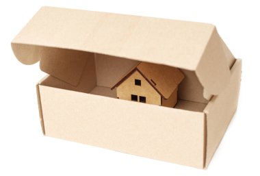 Partly opened cardboard shipping box with a tiny new wooden house inside. Real estate sale concept.