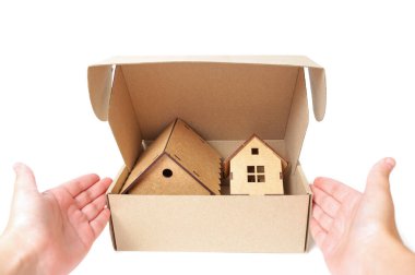 Hand unpacking a shipping box with wooden toy houses isolated on white. Unpack a new house.