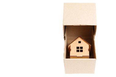 Wooden self-assembly toy house inside a cardboard box isolated on white. Relocation concept.
