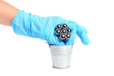 Hand throwing a bunch of corroded dead batteries into a steel bucket isolated on white. Safe household batteries recycling concept.