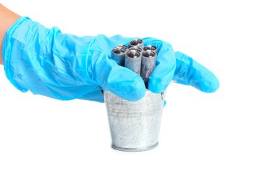 Throwing dead corroded batteries in a small steel bucket isolated on white. Cells recycling concept.