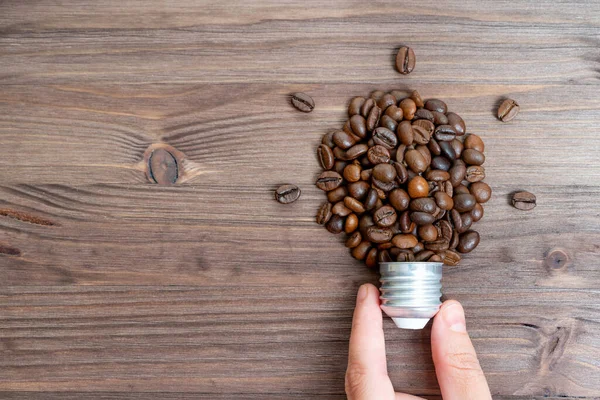 Hand Pinch Holding Lightbulb Made Roasted Coffee Beans Cap Wooden — Fotografia de Stock