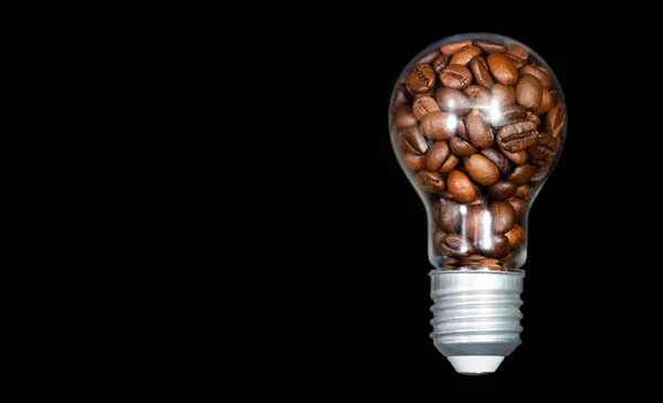 Roasted coffee beans inside an incandescent light bulb isolated on black background with copy space.