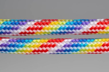 Two rainbow dyed braided cotton cords isolated on gray background.