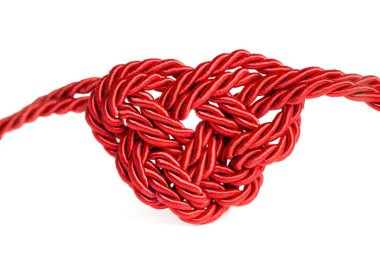 Red heart shaped knot made from threaded cord isolated on white background. Creative romantic concept.