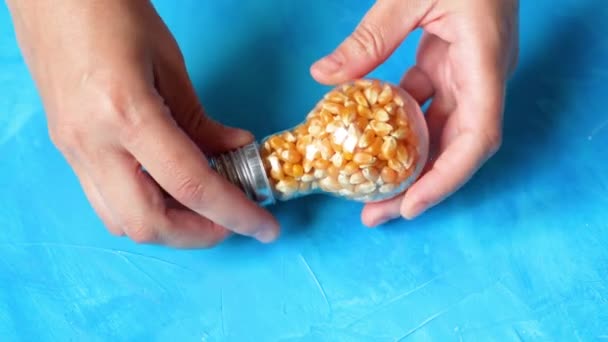 Female Opens Light Bulb Shaped Container Pours Popcorn Kernels Blue — Stock videók