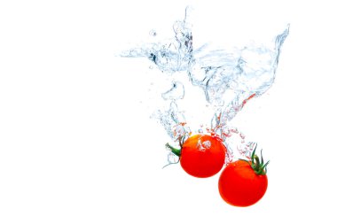 Cherry tomatoes falling underwater with splashes isolated on white background.