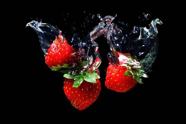 Three Ripe Strawberries Sinking Underwater Splashes Isolated Black Background — Foto Stock