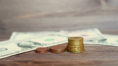 Throwing dollar bills on a wooden table and putting a miniature house model on a coins stack.