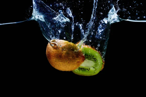 Cut-in-half kiwifruit dropped in water with splashes isolated on black background