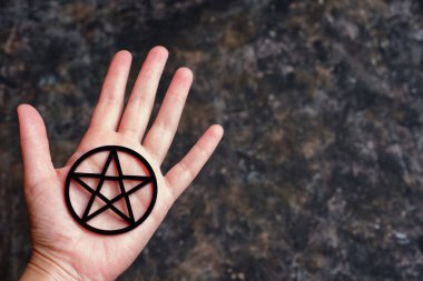Geniş siyah bir pentagram tutan açık bir elin yakın plan fotokopi arkaplanı ile koyu ve kirli bir arka plan