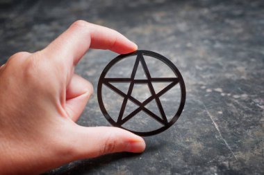 Siyah bir pentagram tutan bir kadının yakın plan çekimleri.
